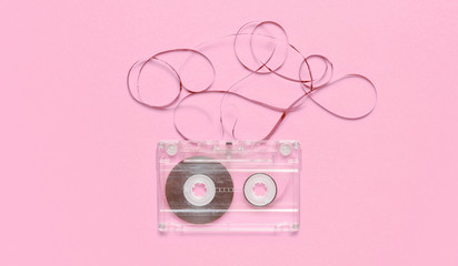Music lover minimalism concept. Retro style 80s. Audio cassette with film on pink pastel paper...