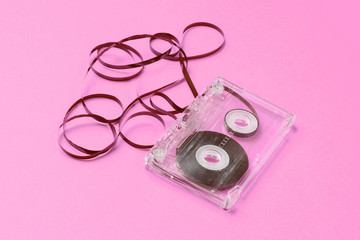 Music lover minimalism concept. Retro style 80s. Audio cassette with film on pink paper background.