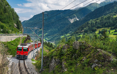 A tourist train traveling on the railway through Sumvitg valley of Switzerland.