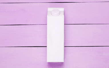White cardboard box of yogurt on pink wooden background. Minimalistic eco food concept