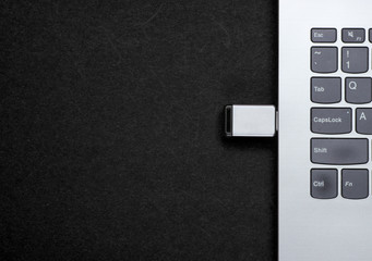 Laptop with flash drive on black background. Top view