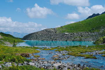 Fototapeta premium Mountain blue lake among rocks. Stone ridge in river valley under clouds. Travel in mountains among hills
