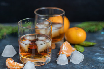 Whiskey in glasses with ice and perspiration on a dark background.