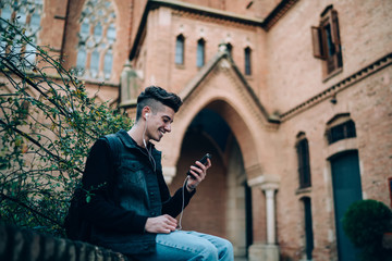 Fototapeta na wymiar Young man with earphones sitting on street