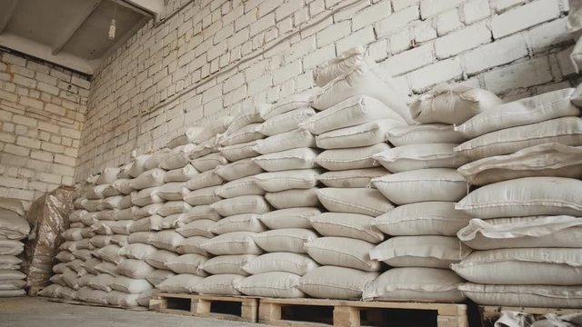 Bags with flour in warehouse of flour factory. Flour stock. Mill warehouse.