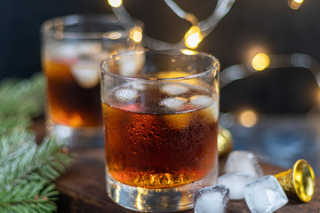 Whiskey in glasses with ice and perspiration on a dark background.