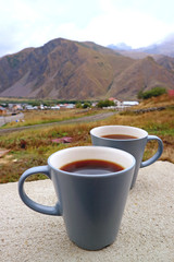 Closeup a Pair of Coffee Mug Cups with Blurry Mountain in the Backdrop