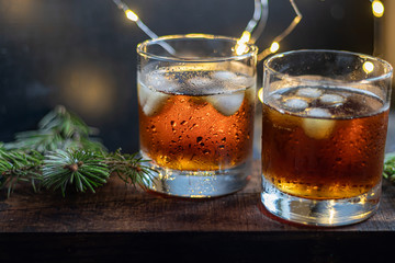 Whiskey in glasses with ice and perspiration on a dark background.