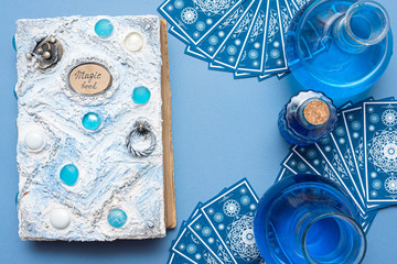 Blue tarot cards deck, white magic book on blue fortune teller background.