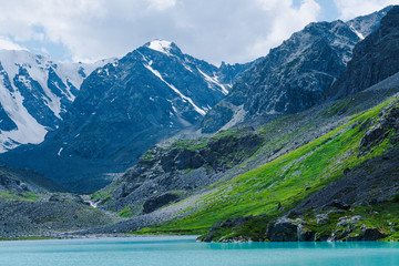 Naklejka na ściany i meble Turquoise lake among mountain peaks. High mountain river on summer day, hiking on rocks and stones