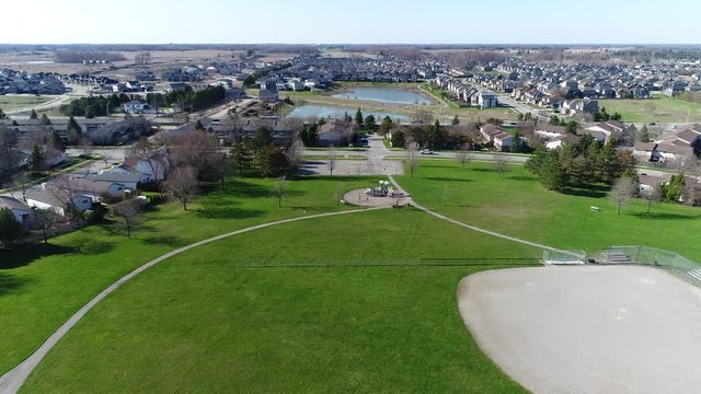 Flying Over Park And Playground Towards Bodies Of Water In Between Houses In Early Spring