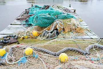 blue fishing net on a pontoon with its ropes and floats covered with morning frost