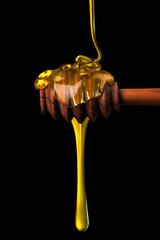 Honey on a wooden dipper isolated on black background with clipping path