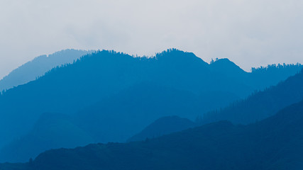 silhouettes of mountains in blue haze. Outline of gentle hills in the valley