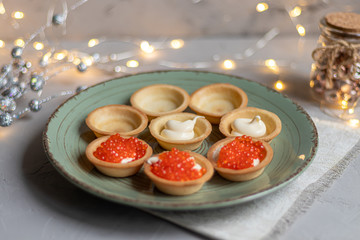 Tartlets with soft cheese, shrimp and red caviar. Holiday dish. On a green plate.