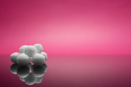 Selective focus of group of mothball isolated in pink background.