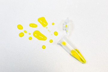 Close up of an artistic yellow blots on a white background spilled from an open plastic test tube. Disposable tableware in the modern world. Medicine fnd healthcare