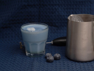 blue matcha latte and pitcher with milk on blue kitchen towel