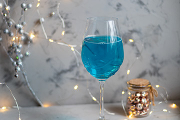 Blue wine in a glass on a dark background. In the background bokeh of lights. Festive mood.