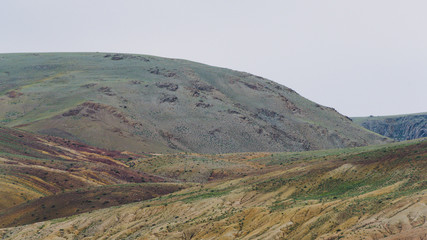gentle red hills, journey through mountain valley, pastures for animals, soil erosion in arid steppe