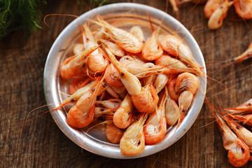 Boiled shrimps on plate on wooden table