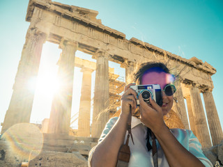Young woman tourist taking pictures at parthenon in Athens acropolis, Greece