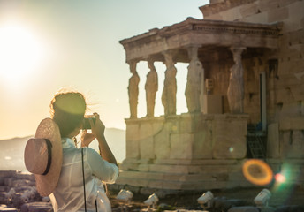 Young woman tourist taking pictures at parthenon in Athens acropolis, Greece - obrazy, fototapety, plakaty