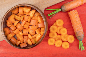 freshly cut carrot slices in plate on red wooden table, cooking vegetarian salad for healthy eating