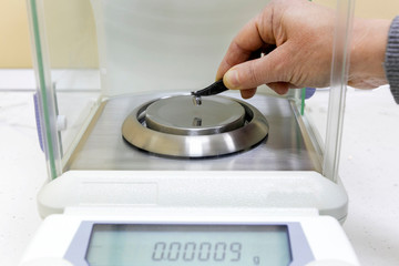The student weighs a small metal object on an accurate analytical balance.