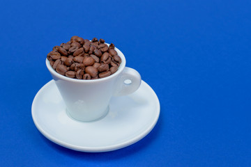 offee beans in a coffee cup isolated from above on a blue background. with clipping path.