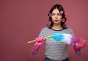 Sad beautiful girl in curlers does not want to clean up.