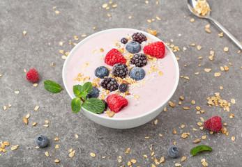 Berry smoothie bowl topped with blueberries, raspberry, blackberry, coconut flakes, yoghurt, muesli and mint for healthy breakfast, selective focus. Vegan food
