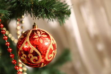 Decorated fir tree with colored red ball, golden pine cones blurred background, shallow depth of field