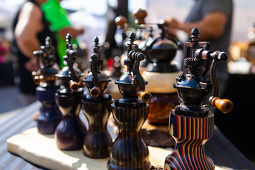 Selective focus and close up view of handmade wood and metal salt and pepper grinders for sale on a...