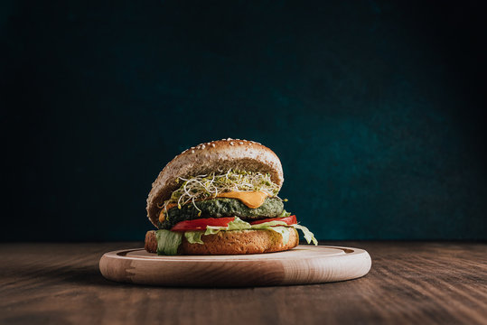 Meat burger and vegan hamburger on top of wooden board, centered on the table. Copy space design