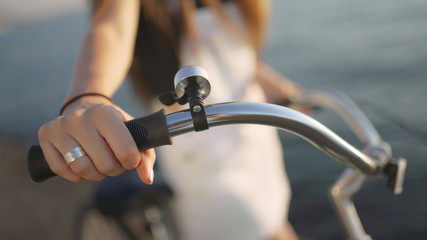 Obraz premium Young beautiful woman with a bicycle is having a good time at the sea at sunset or sunrise 