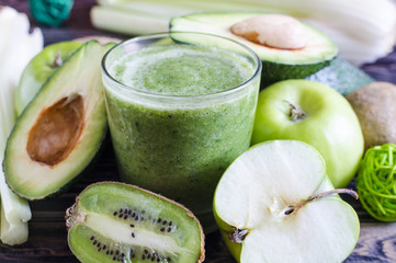 fruit and greens smoothie in a clear glass in the foreground healthy eating concept