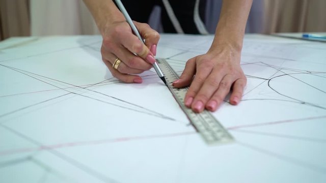 Creative designer drawing clothes pattern on paper in atelier