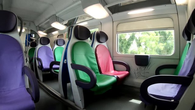 Modern train interior with colorful leather seats and clean carriages. High-speed train passing stops, public transportation in Europe. Express train destinating railway station