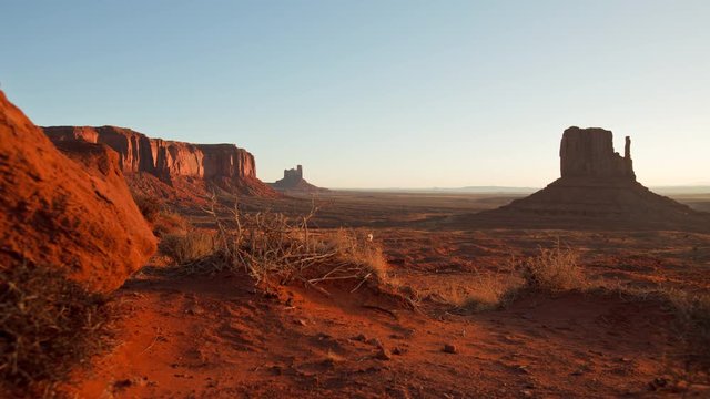 Time Lapse of dawn at Monument Valley. Camera moves past tumbleweeds with the buttes of Monument Valley Arizona in the background.