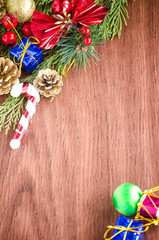Green spruce branches. Brown wooden background. White, red, multi-colored Christmas toys. Decorations for Christmas tree made of wood and ceramics. Festive fun concept. Congratulatory backdrop. 