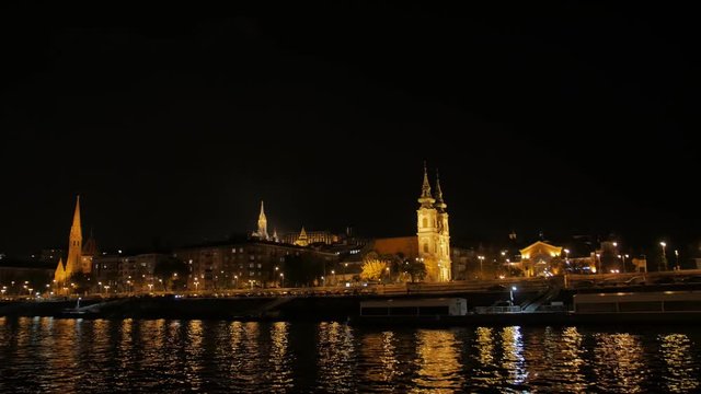 Churches by the river night boat view with illumination in Budapest Hungary Danube river tracking camera movement