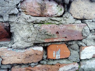 Brick wall. Ceramic masonry or fence. Old, uneven brick, covered in some places with moss and mold....