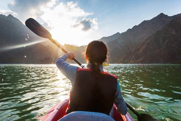Woman kayaking in a lake at sunset - obrazy, fototapety, plakaty