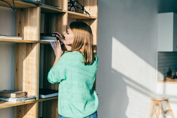 Young woman searching book at shelf