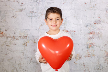 Fototapeta na wymiar Happy little boy with a heart shaped balloon