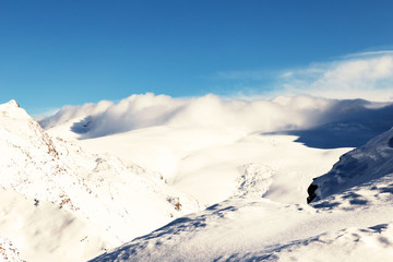Panorama with snowy mountains, and clouds passing over.