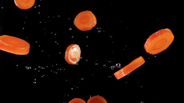 Fresh choped organic carrots flying up to the camera on a black background