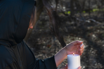 White burning Candle in woman's hands in the middle of the forest. Hope and Pray concept. All...