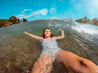 Girl floating in the water and splashed by the waves
